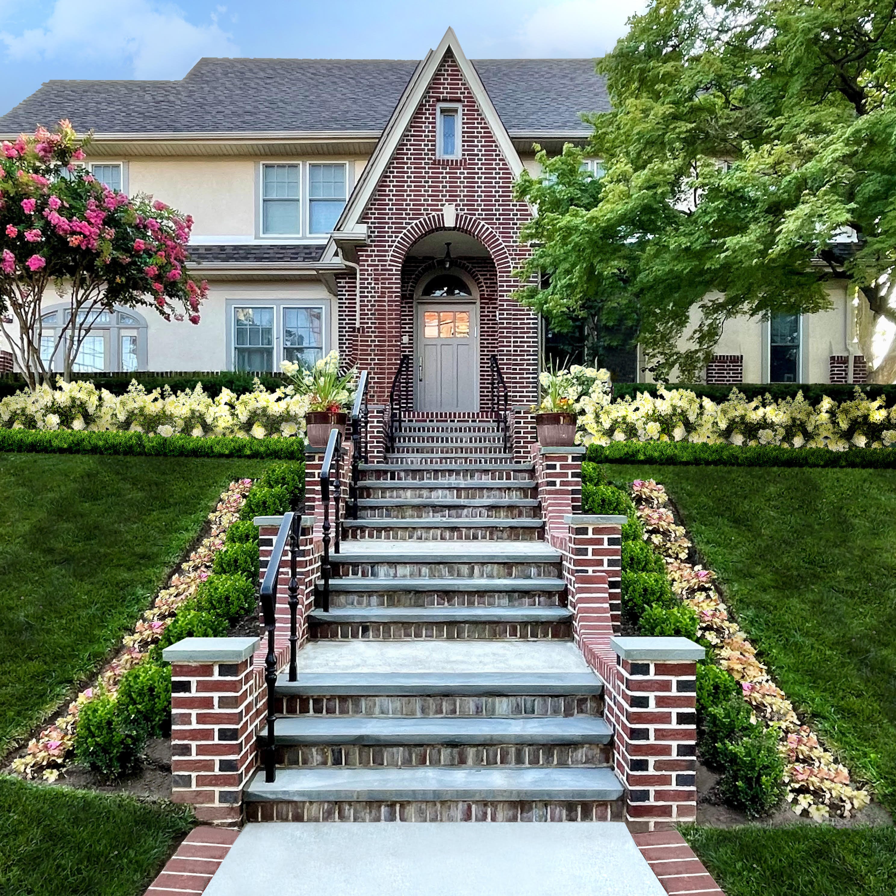 Brick staircase leading up to a house with decorative plants on either side.